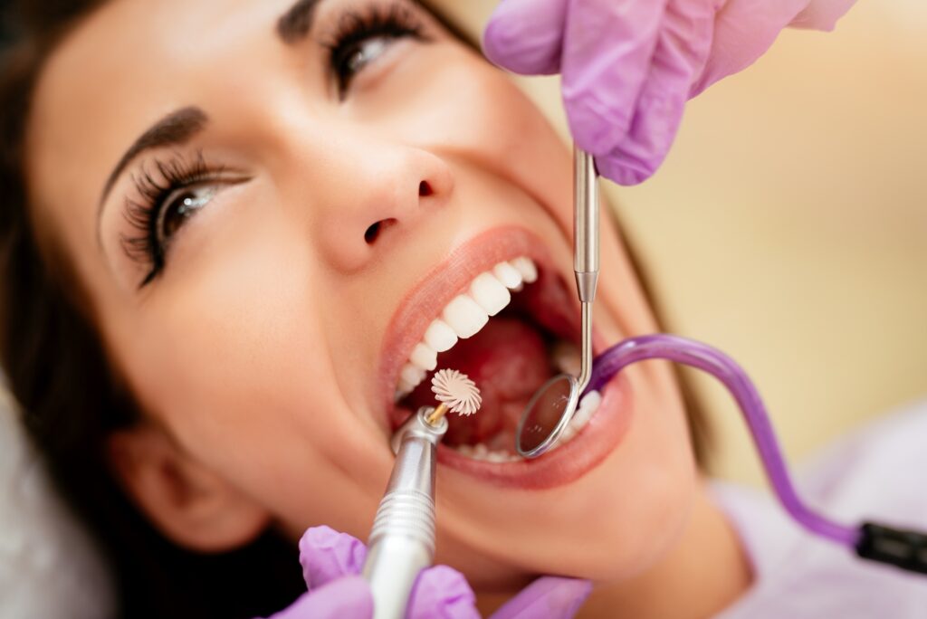Smiling woman receiving a professional dental cleaning with dental tools visible