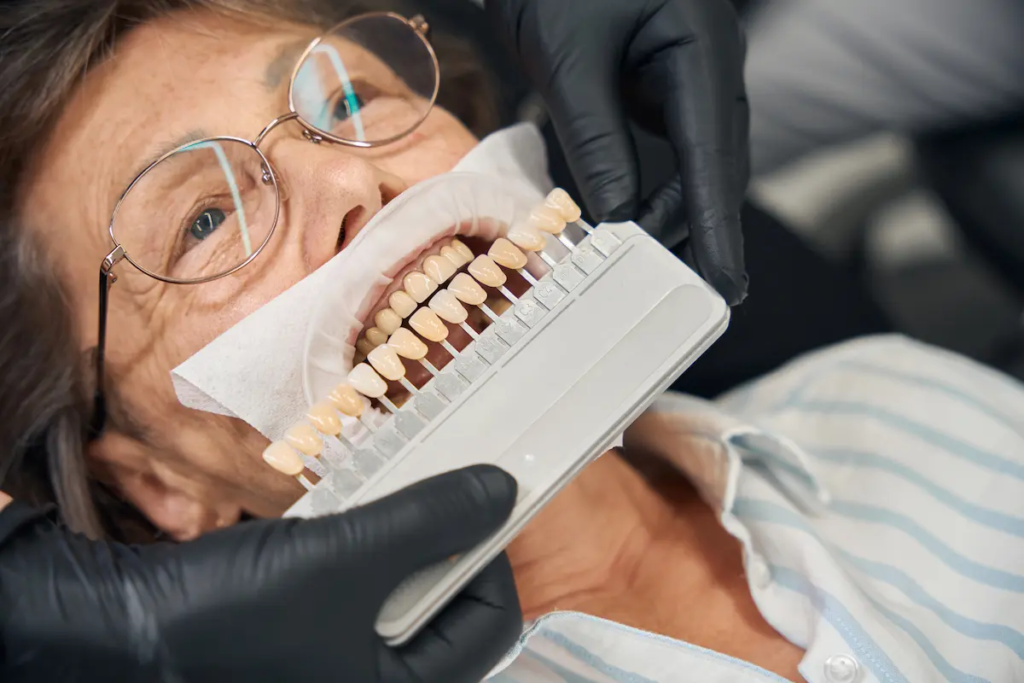 Dentist matches dental shade for elderly patient.