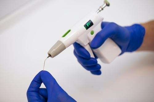 Gloved hands using dental syringe tool.